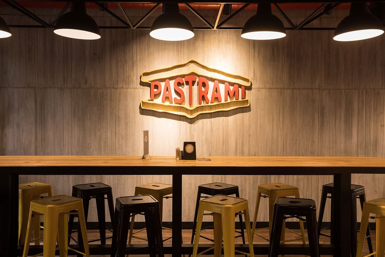 фото коммуникабельного стола и стена с фирменным логотипом в ресторане ПАСТРАМИ