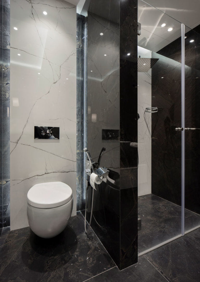 photo of shower room with toilet and contrast of black and white natural marble