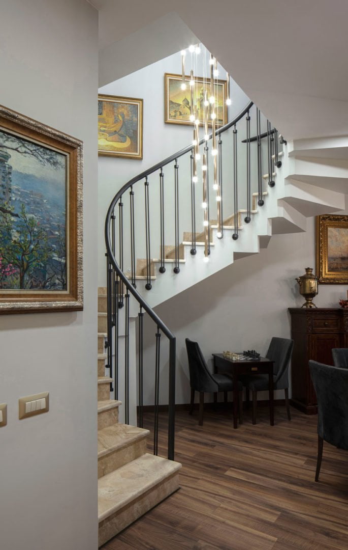 photo of a staircase with graphite-colored railings and paintings from the collection of the owners of the apartment