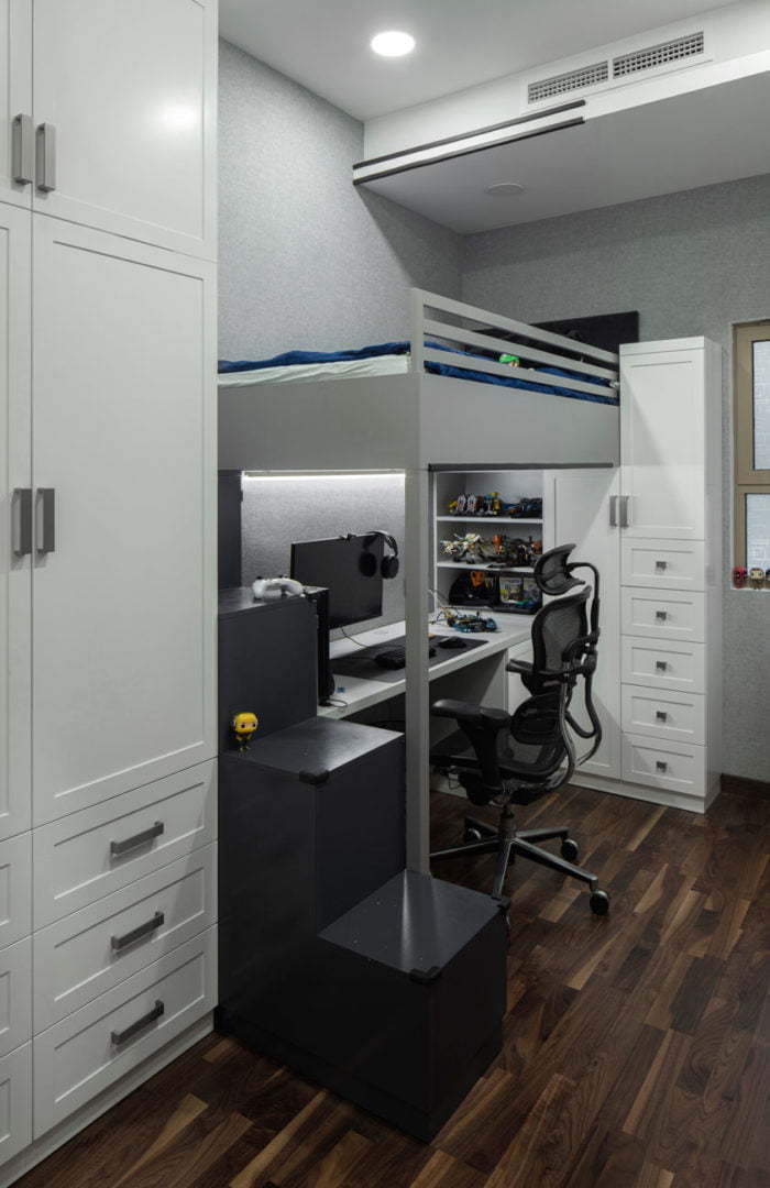 photo of a children's room with a bunk bed a workplace and two white cabinets